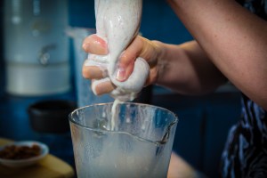 Squeezing the almond milk through the nut milk bag